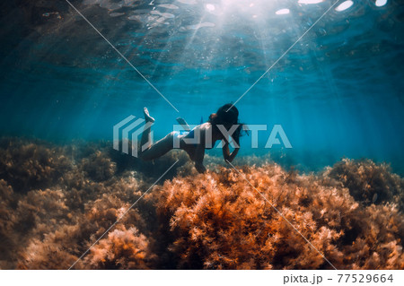 Woman with diving mask posing underwater in transparent ocean with sun rays 77529664