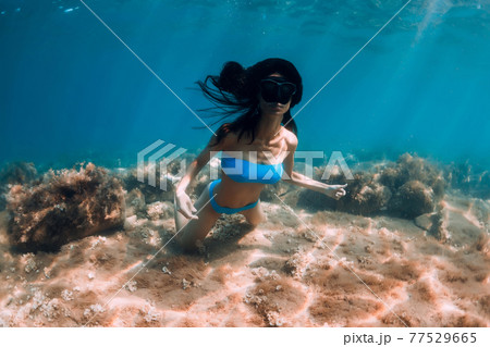 Woman with diving mask posing underwater in transparent ocean with sun rays 77529665