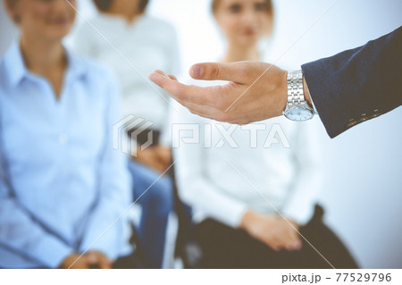 Business man making presentation to group of people, close-up. Speaker delivering a seminar to his colleagues or business training in office. Teamwork and coaching concept 77529796