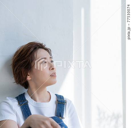 ジェンダーレス　LGBT 男の子みたいな女の子　オーバーオールを着て座る若い女性　正方形 77530074