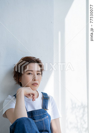 ジェンダーレス　LGBT 男の子みたいな女の子　オーバーオールを着て座る若い女性 77530077