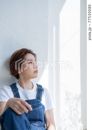 ジェンダーレス Lgbt 男の子みたいな女の子 オーバーオールを着て座る若い女性の写真素材