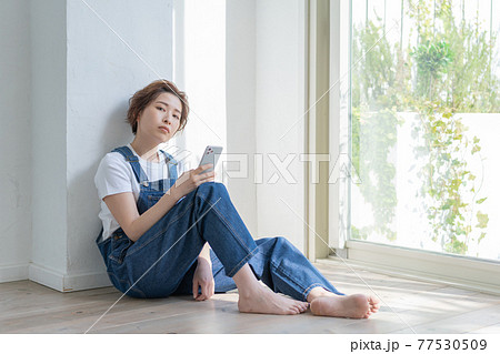 ジェンダーレス LGBT 男の子みたいな女の子 床に座ってスマホを手にする若い女性 ジェンダーレス LGBT 男の子みたいな女の子 床に座ってスマホを手にする若い女性 77530509