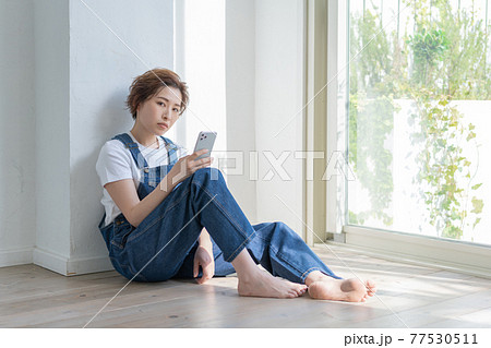 ジェンダーレス LGBT 男の子みたいな女の子 床に座ってスマホを手にする若い女性 ジェンダーレス LGBT 男の子みたいな女の子 床に座ってスマホを手にする若い女性 77530511