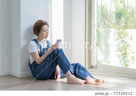 ジェンダーレス LGBT 男の子みたいな女の子 床に座ってスマホを手にする若い女性 ジェンダーレス LGBT 男の子みたいな女の子 床に座ってスマホを手にする若い女性 77530512