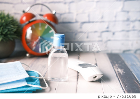 Surgical masks, thermometer and hand sanitizer on orange background  77531669