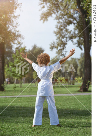 Little girl in white karate kimono standing on the street 77532451