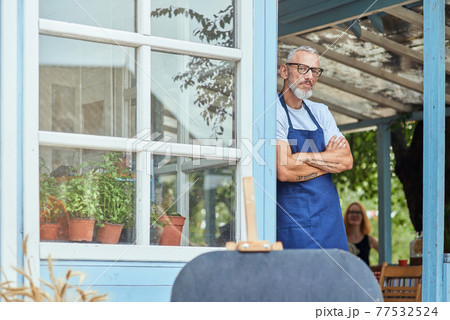 Middle aged caucasian man leaning on garden house wall 77532524