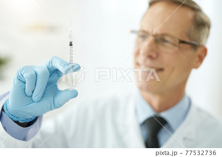 Cheerful male doctor holding syringe with vaccine 77532736
