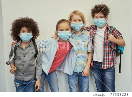 Cheerful diverse children wearing protective face masks looking at camera, posing together over light background Cheerful diverse children wearing protective face masks looking at camera, posing together over light background 77533223