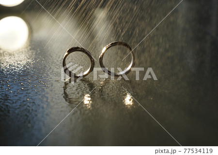 two wedding gold rings reflected in the mirrored surface under the water drops two wedding gold rings reflected in the mirrored surface under the water drops 77534119