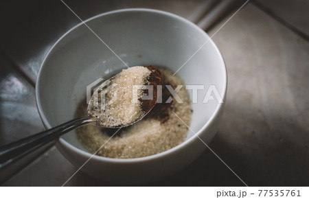 Measuring sugar and instant coffee powder by tablespoon into a white bowl. preparing ingredients for making Dalgona coffee foam. a spoonful of sugar and coffee mixture overhead close up view. Measuring sugar and instant coffee powder by tablespoon into a white bowl. preparing ingredients for making Dalgona coffee foam. a spoonful of sugar and coffee mixture overhead close up view. 77535761