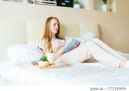 Blonde woman in bed with book Blonde woman in bed with book 77536909