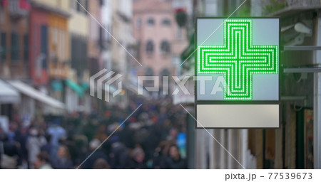 Pharmacy sign with green cross in busy street 77539673