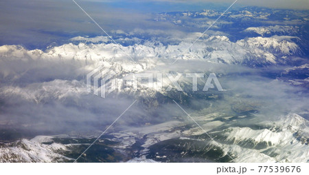 Flying over the snowy mountains 77539676