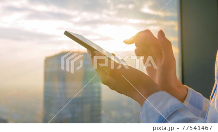 Woman using smartphone device against cityscape view at sunset - close up view 77541467