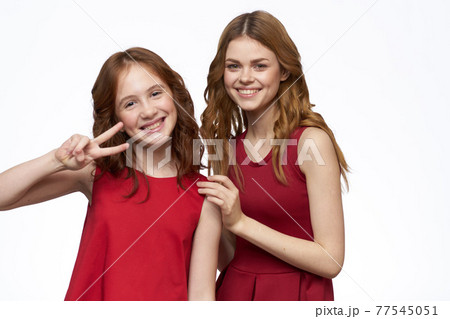 Cheerful mom and daughter next to red dresses hugs lifestyle light background smile 77545051