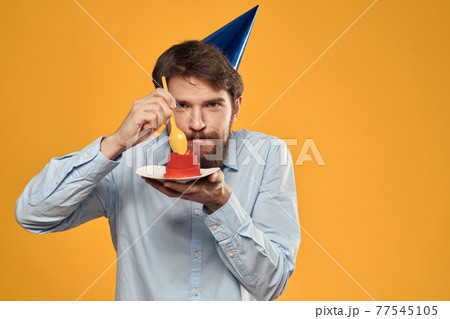 a man with a birthday cake in his hands and in a cap on a yellow background on his birthday a man with a birthday cake in his hands and in a cap on a yellow background on his birthday 77545105