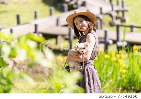 小型犬と一緒に散歩する若い女性　北柏ふるさと公園 77549360