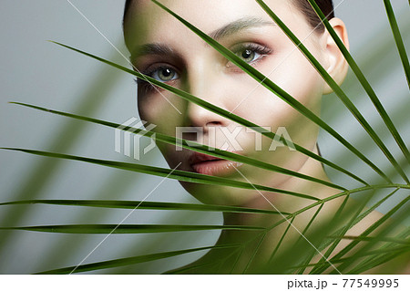 beautiful girl in palm leaves. Beautiful young woman with Make-up beautiful girl in palm leaves. Beautiful young woman with Make-up 77549995