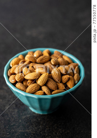 Almond nuts in bowl on black table. 77550778