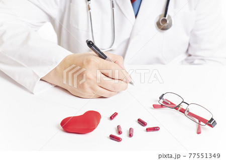 Doctor writing next to a red heart and pills. Heart checkup Doctor writing next to a red heart and pills. Heart checkup 77551349