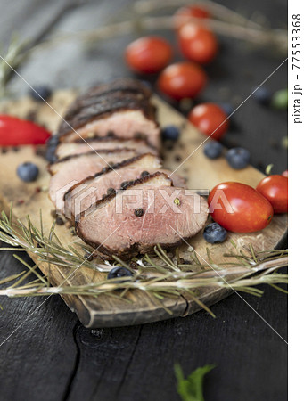 Goose breast Christmas roast with blueberries, tomatoes, red peppers and rosemary served on a wooden board Goose breast Christmas roast with blueberries, tomatoes, red peppers and rosemary served on a wooden board 77553368