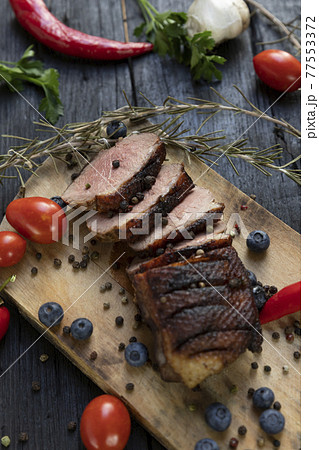 Goose breast Christmas roast with blueberries, tomatoes, red peppers and rosemary served on a wooden board Goose breast Christmas roast with blueberries, tomatoes, red peppers and rosemary served on a wooden board 77553372