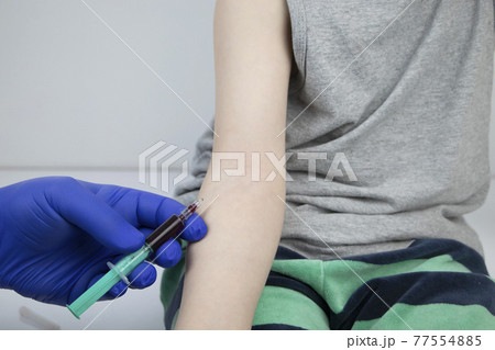 The doctor takes the boy blood from a vein. Taking blood from a child for research and laboratory analysis 77554885
