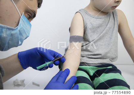The doctor takes the boy blood from a vein. Taking blood from a child for research and laboratory analysis The doctor takes the boy blood from a vein. Taking blood from a child for research and laboratory analysis 77554890