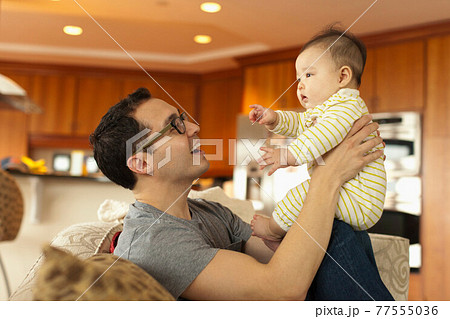 Close up of father sitting on sofa with baby daughter 77555036