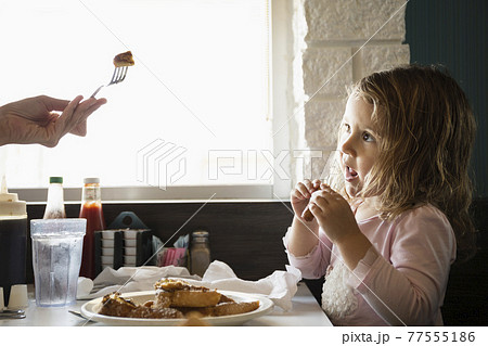 Hand of mother feeding toddler daughter in diner Hand of mother feeding toddler daughter in diner 77555186
