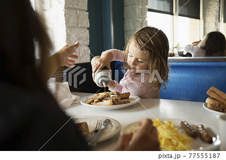 Mother with toddler daughter pouring ketchup in diner 77555187