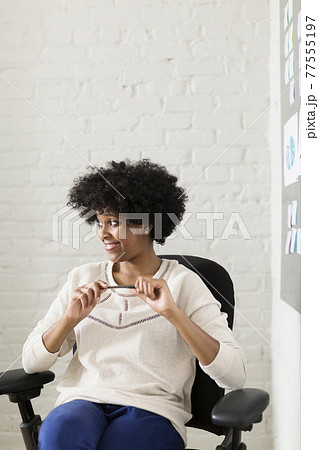 Portrait of young woman sitting in office chair looking away Portrait of young woman sitting in office chair looking away 77555197