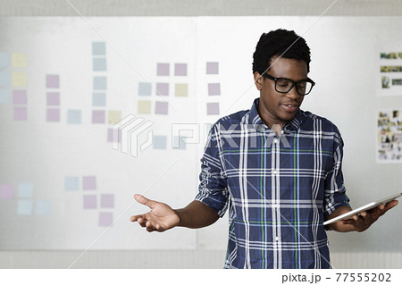 Young man holding digital tablet with arms out 77555202