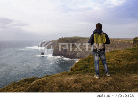 Mid adult man standing on The Cliffs of Moher, The Burren, County Clare, Ireland 77555316