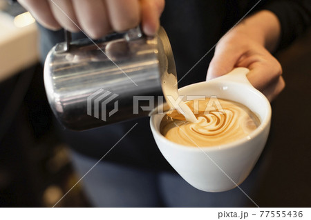 Coffee shop barista pouring milk into coffee, mid section, close-up Coffee shop barista pouring milk into coffee, mid section, close-up 77555436