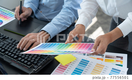 Graphic designer or creative working together coloring using graphics tablet and a stylus at desk with colleague. Graphic designer or creative working together coloring using graphics tablet and a stylus at desk with colleague. 77556501