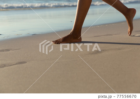 Low section of mixed race woman on beach practicing yoga durning sunset 77556670
