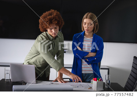 Diverse male and female colleagues in office discussing over blueprint document Diverse male and female colleagues in office discussing over blueprint document 77557482