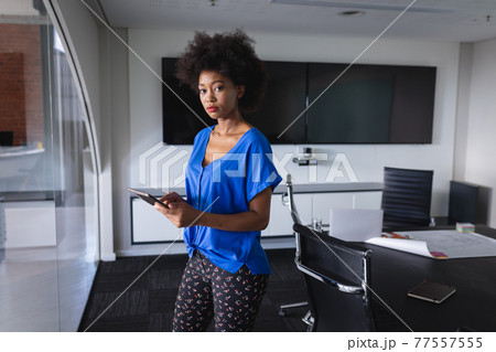 African american business woman in meeting room standing over blueprint document 77557555
