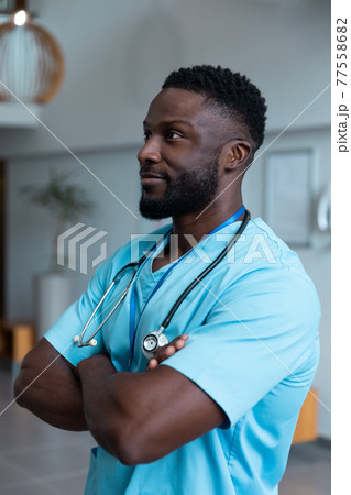 Portrait of african american male doctor with stethoscope wearing scrubs in hospital 77558682