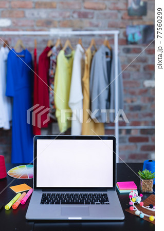 Laptop with copy space on screen lying on desk full of designers accessories 77560299