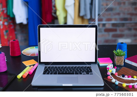 Laptop with copy space on screen lying on desk full of designers accessories 77560301