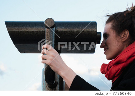 A young girl looks through a large city binoculars. City landmarks 77560340