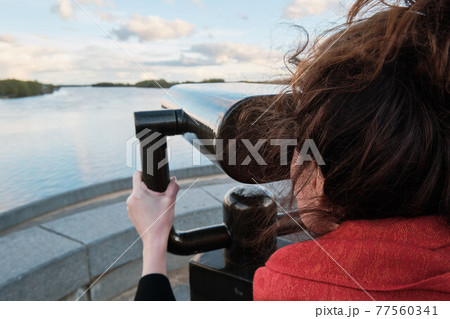 A young girl looks through a large city binoculars. City landmarks 77560341
