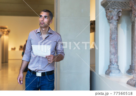 Adult man is visiting museum and looking at the exposition 77560518