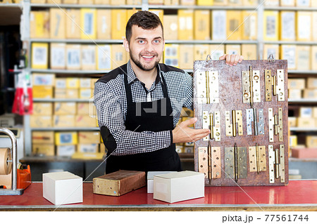 Shop assistant displaying door and furniture knobs 77561744