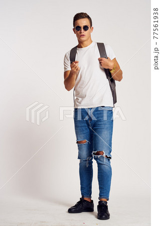 a man with a backpack on his back in jeans t-shirt full length sneakers and glasses on his face a man with a backpack on his back in jeans t-shirt full length sneakers and glasses on his face 77561938