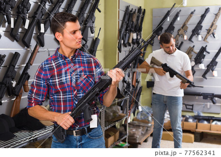 Young male is choosing air-powered gun Young male is choosing air-powered gun 77562341